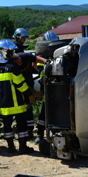 Firefighters attending to an overturned vehicle at an accident scene. Daylight outdoor operation.