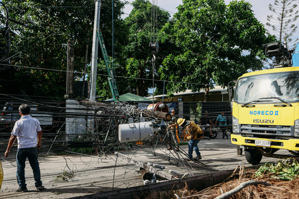 Team of workers in hard hats repairing electrical lines from a fallen pole after an accident.